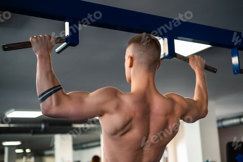 Preview: Bodybuilder performs a pull-up exercise at a gym, showcasing his muscular back.