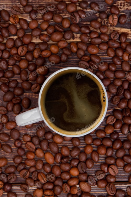Preview: Top view cup of hot coffee standing amoung coffee beans.