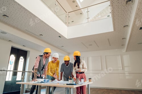 Preview: Multiracial team of architects having a meeting while using blueprints