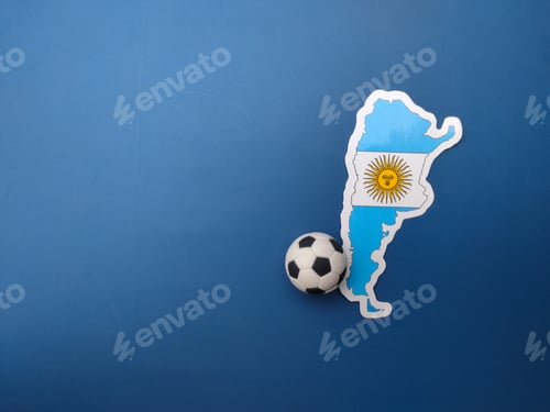 Preview: Top view Argentina flag sticker and ball on a blue background.