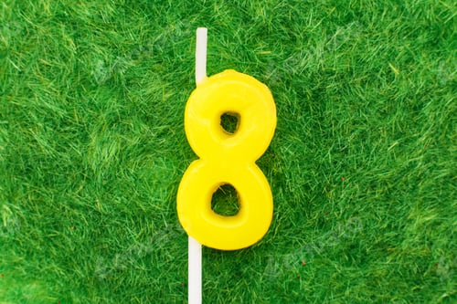 Preview: candle in the form of number 8 on the green grass background, a place for a greeting text
