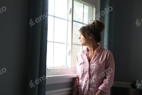 Preview: Woman looking out window somber look