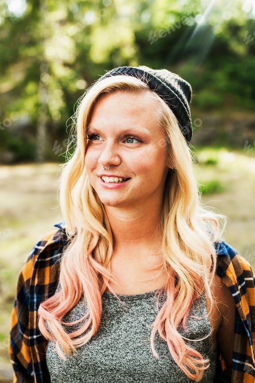 Preview: Thoughtful young woman smiling while looking away at forest