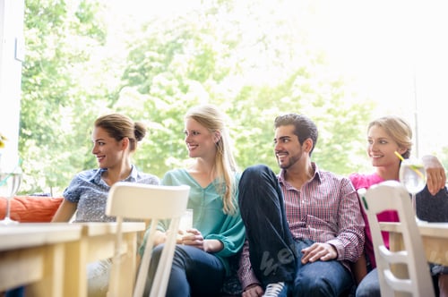 Preview: Small group of young adults sitting side by side in window seat looking away smiling