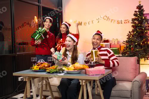 Visualização: Dois rapazes bonitos e duas lindas moças usando chapéus de Natal rindo alegremente