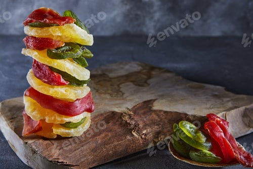 Preview: Dried fruits: yellow candied pineapple rings, red papaya and green kiwi stacked on wooden