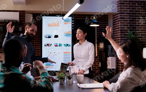 Preview: Woman raising hand to ask a question in late night business meeting with sales department