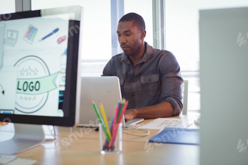 Preview: Serious graphic designer using laptop in creative office