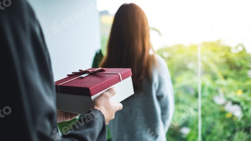 Preview: A boyfriend holding a gift box behind his girlfriend back to surprising her