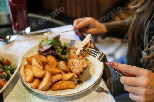 Preview: side view woman eating fried chicken with potatoes