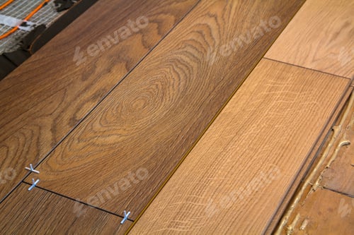 Preview: Renovation works. Close-up of installation of parquet and ceramic tile floor and heating cables for