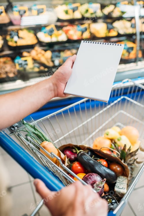 Preview: cropped shot of man holding empty notebook while shopping in supermarket