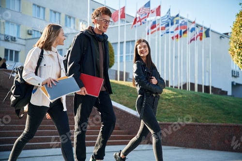 Preview: Going by the stairs. Three young students are outside the university outdoors