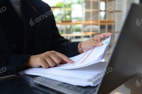 Preview: Professional businesswoman working with financial reports and using laptop at desk