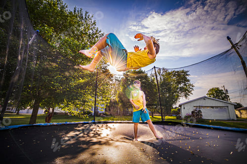 Preview: Brothers jumping on the trampoline in backyard