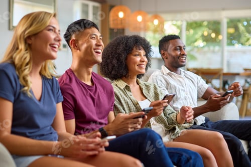 Preview: Group Of Excited Multi-Racial Friends Sitting On Sofa Playing Computer Games Together