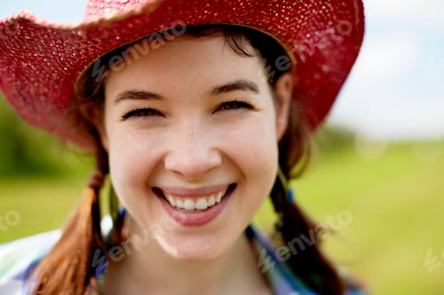 Preview: A young woman in a pink straw hat smiling broadly.