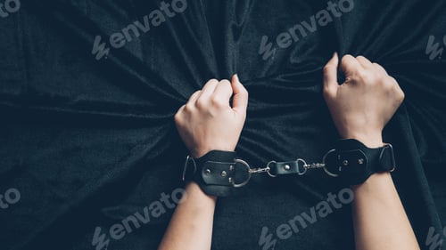 Preview: partial view of woman in leather handcuffs holding black fabric