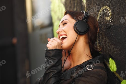 Preview: Young woman enjoys music via headphones on the street