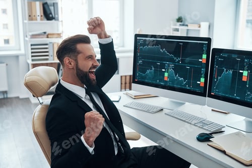 Preview: Happy young man in shirt and tie cheering and gesturing while working in the office