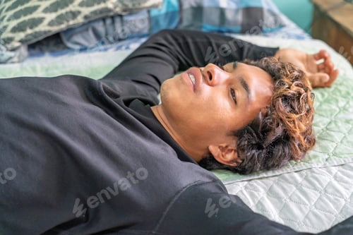 Preview: Young man relaxing on bed with arms outstretched