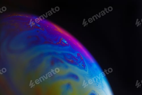 Preview: Rainbow soap bubble on a black background. Close-up of a colorful surface.