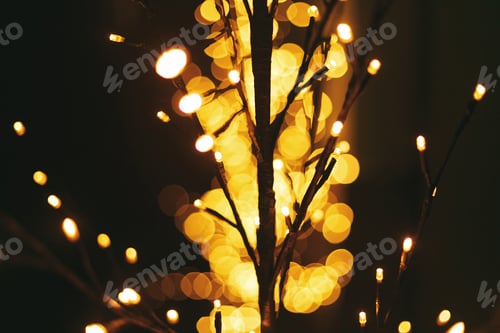Preview: Stylish illuminated tree with warm golden lights bokeh, festive decor in evening. Winter holiday