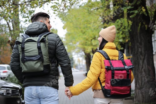 Preview: Couple with travel backpacks on city street, back view. Urban trip