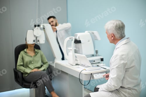 Preview: Senior Ophthalmologist Examining Female Patient with Eye Equipment