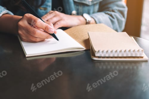 Preview: Closeup image of a woman writing on a blank notebook on the table