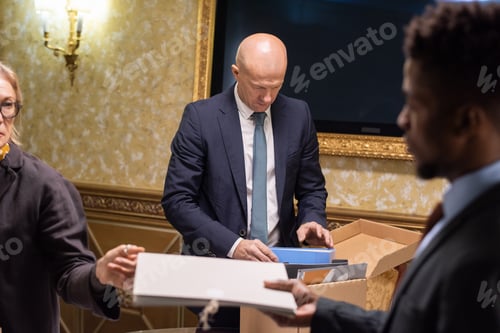 Preview: African male lawyer taking folder with papers given by female colleague
