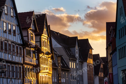 Preview: Part of a building under the sun surrounded by many others under a sky full of clouds