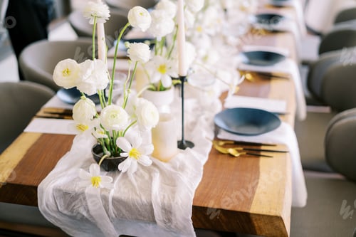 Preview: Bouquets of white flowers stand on a narrow fabric on a festive table with black plates