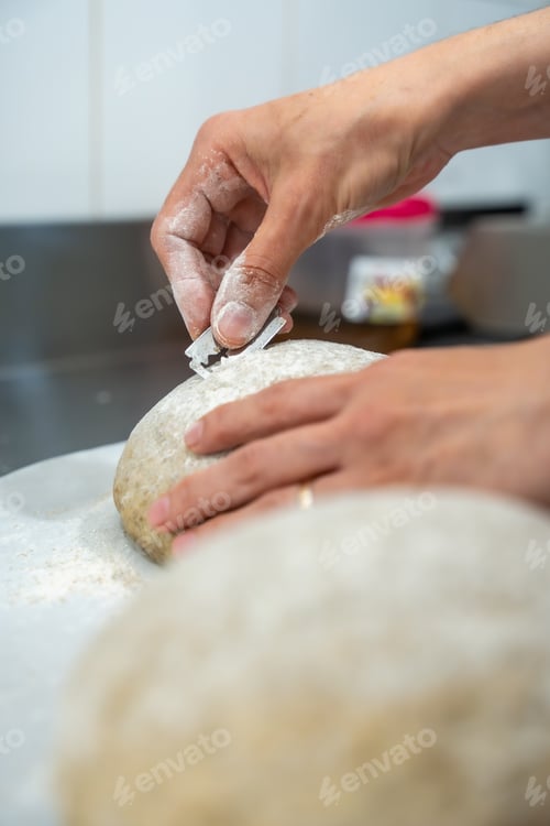 Preview: Baker scoring sourdough bread dough with razor blade for baking