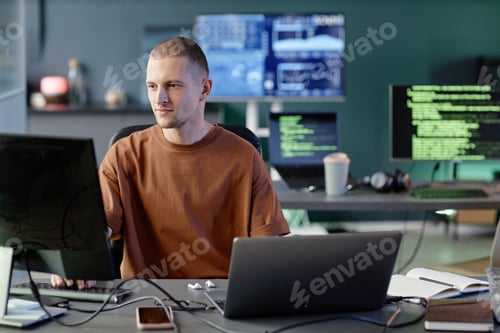 Preview: Calm Male Programmer Coding on Computer Working alone at Desk with Laptop in Office