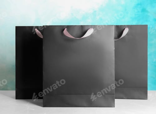Preview: Paper shopping bags on table against color background. Mock up for design
