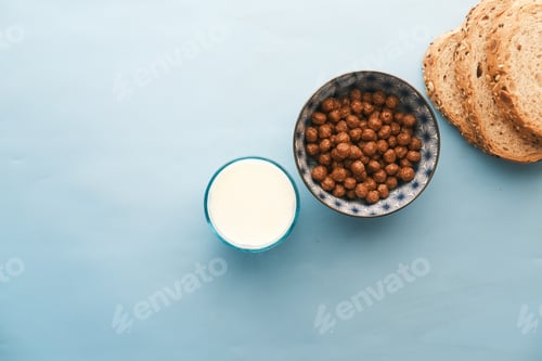 Preview: Top view of chocolate corn flakes , milk and bread on blue