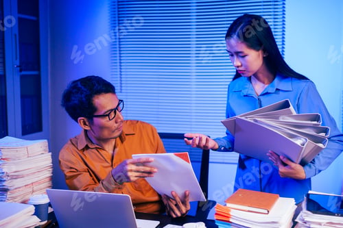 Preview: A businessman and woman are working overtime at their desks office at night.They are busy,stressed
