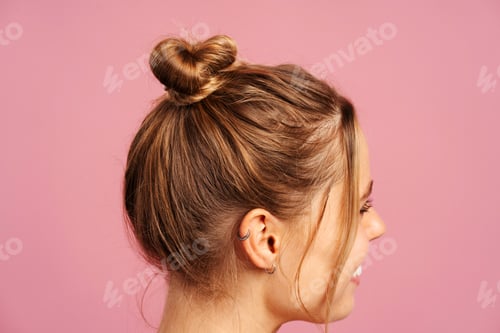 Preview: Young sporty woman with hair bun on pink background, posing in studio, close up