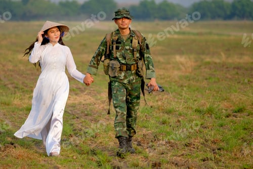 Preview: Soldier man holds hand of Vietnamese woman and walk in the field with evening light