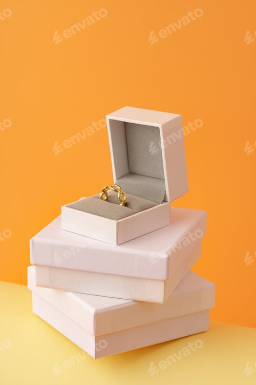 Preview: Golden ring in white jewelry box on yellow background