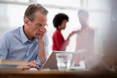 Preview: Man Works at Desk with Coworkers in Background