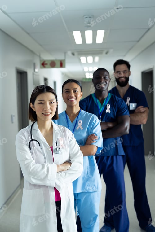 Preview: Vertical portrait of diverse group of smiling healthcare workers wearing cancer ribbons, copy space
