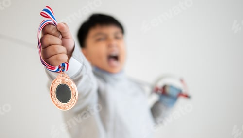 Preview: A happy Asian boy fencer bit a gold medal, celebrating success