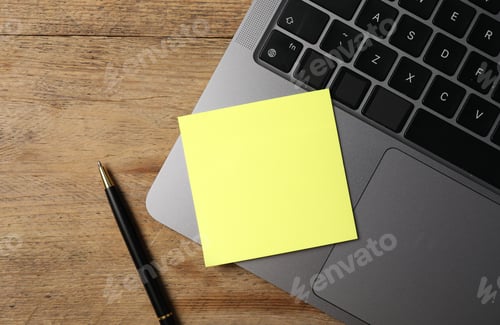 Preview: Laptop with sticky note and pen on wooden table, top view