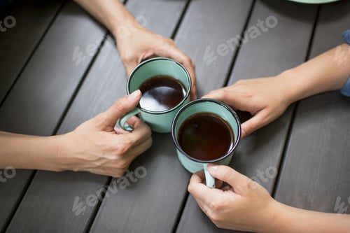Preview: Two people seated at a table, drinking coffee, viewed from above.
