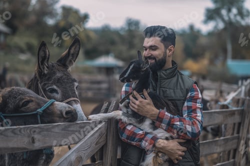 Preview: A happy farmer holding a cute goatling
