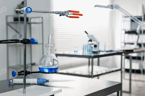Preview: Flask with blue liquid on retort stand in laboratory. Space for text