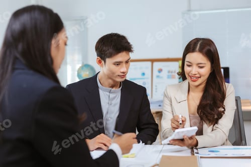 Preview: Asian business team collaborating on finance planning using calculator
