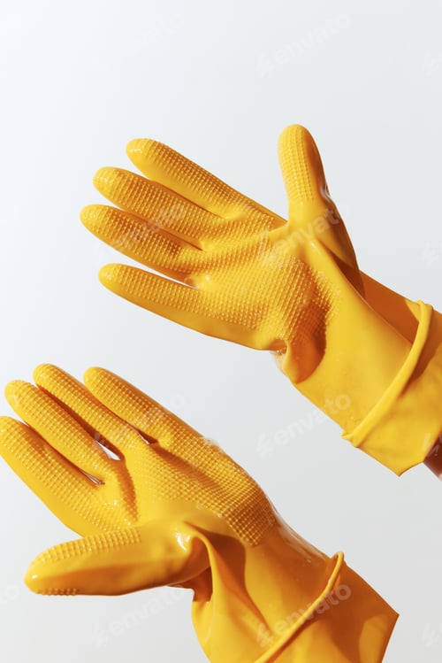 Preview: Pair of yellow rubber gloves held up by a person in a white shirt